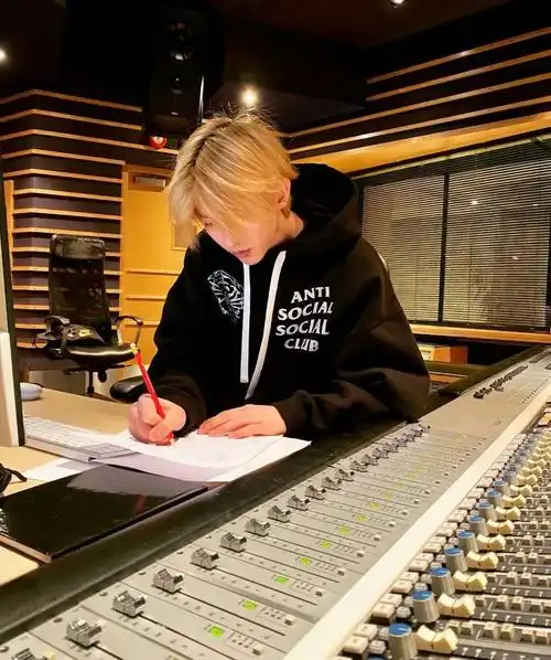 照片中蔡徐坤正在认真写歌,周围是各种录音设备