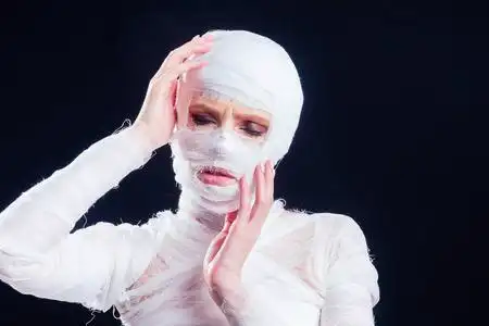 迷人的木乃伊女人全身缠着绷带,背景是黑色的工作室.