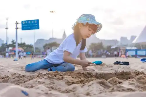 小女孩坐在沙滩上专注的玩沙