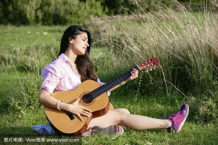 在大自然中抱着吉他弹奏的女孩肖像.