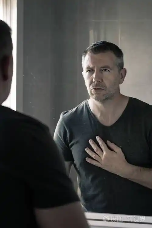 穿着灰色v领t恤的男人在浴室镜子里盯着自己看照片-正版商用图片27buw