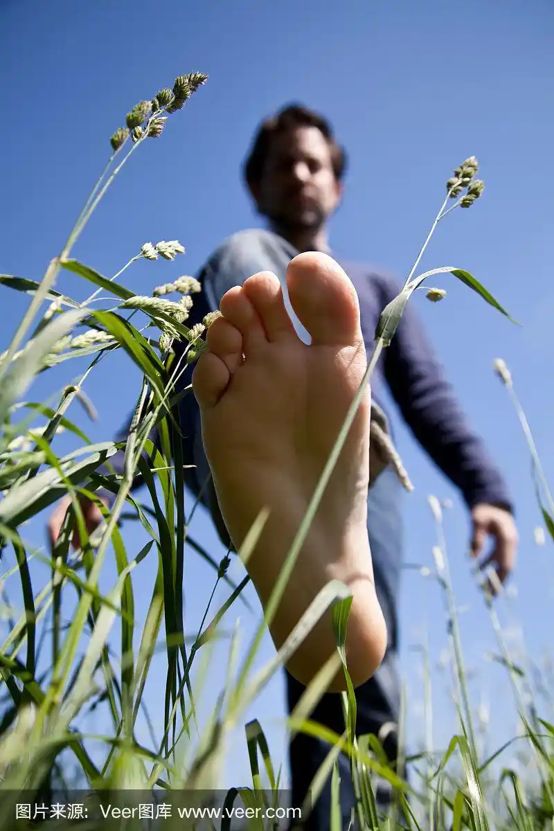 年轻人赤着脚在绿草地上