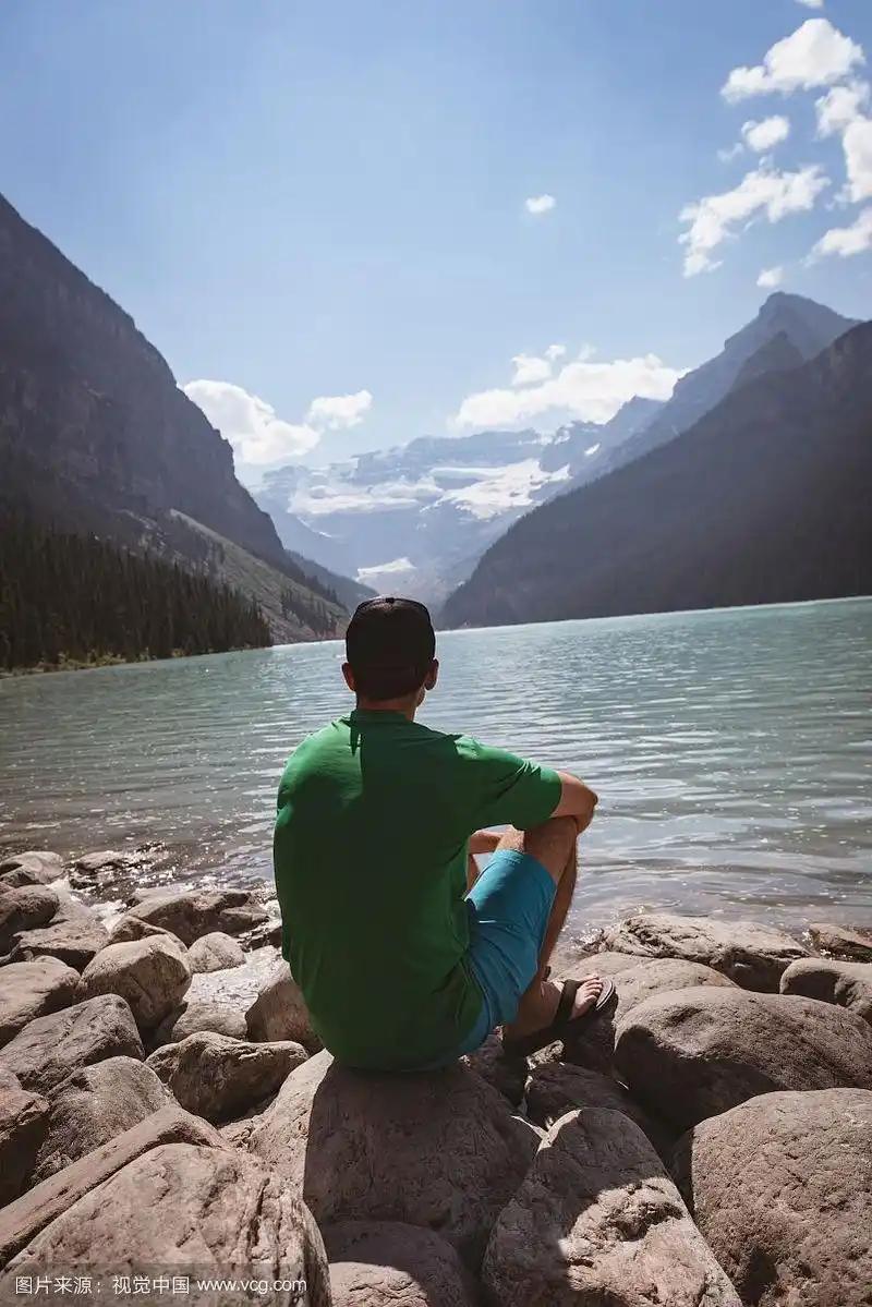 坐在湖边的男人的后视图