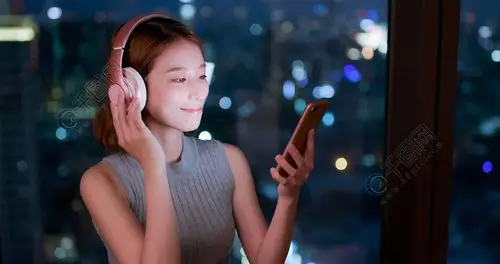 妇女使用电话听音乐在建筑在夜间