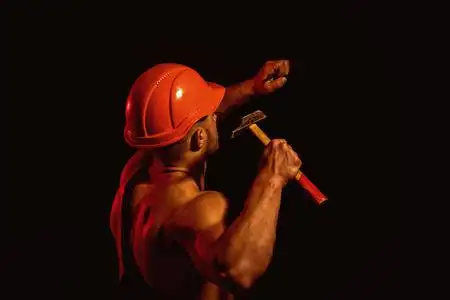 努力工作的人使用肌肉力量.人的工作与锤子.建筑工人钉了一颗钉子.