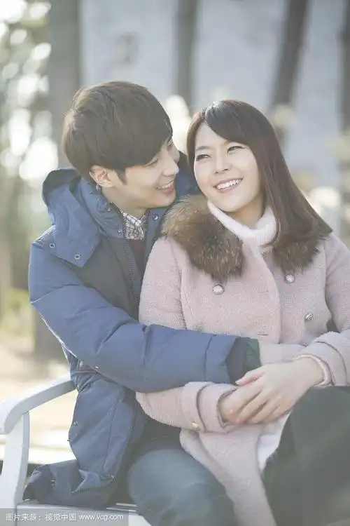 一对年轻情侣坐在长椅上拥抱