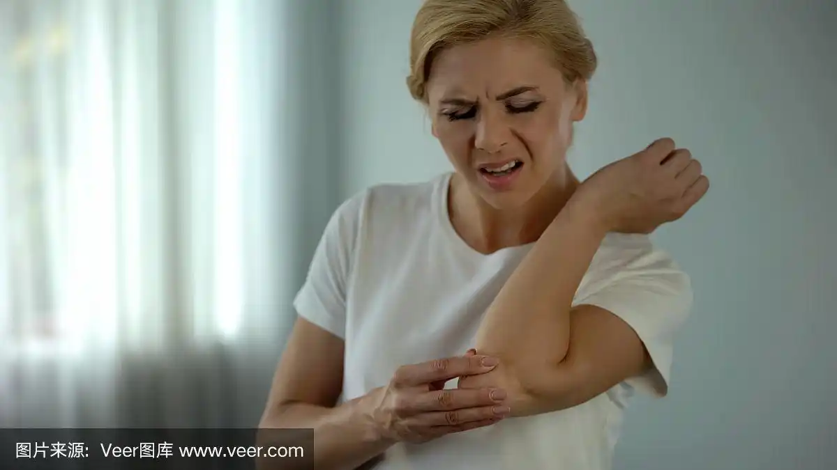 金发女人肘部疼痛,抱着疼痛的手臂,受伤和抽筋