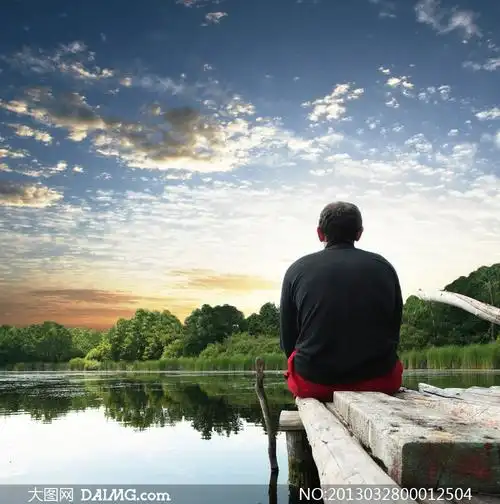 背着坐在木桥上看远方的男人图片素材