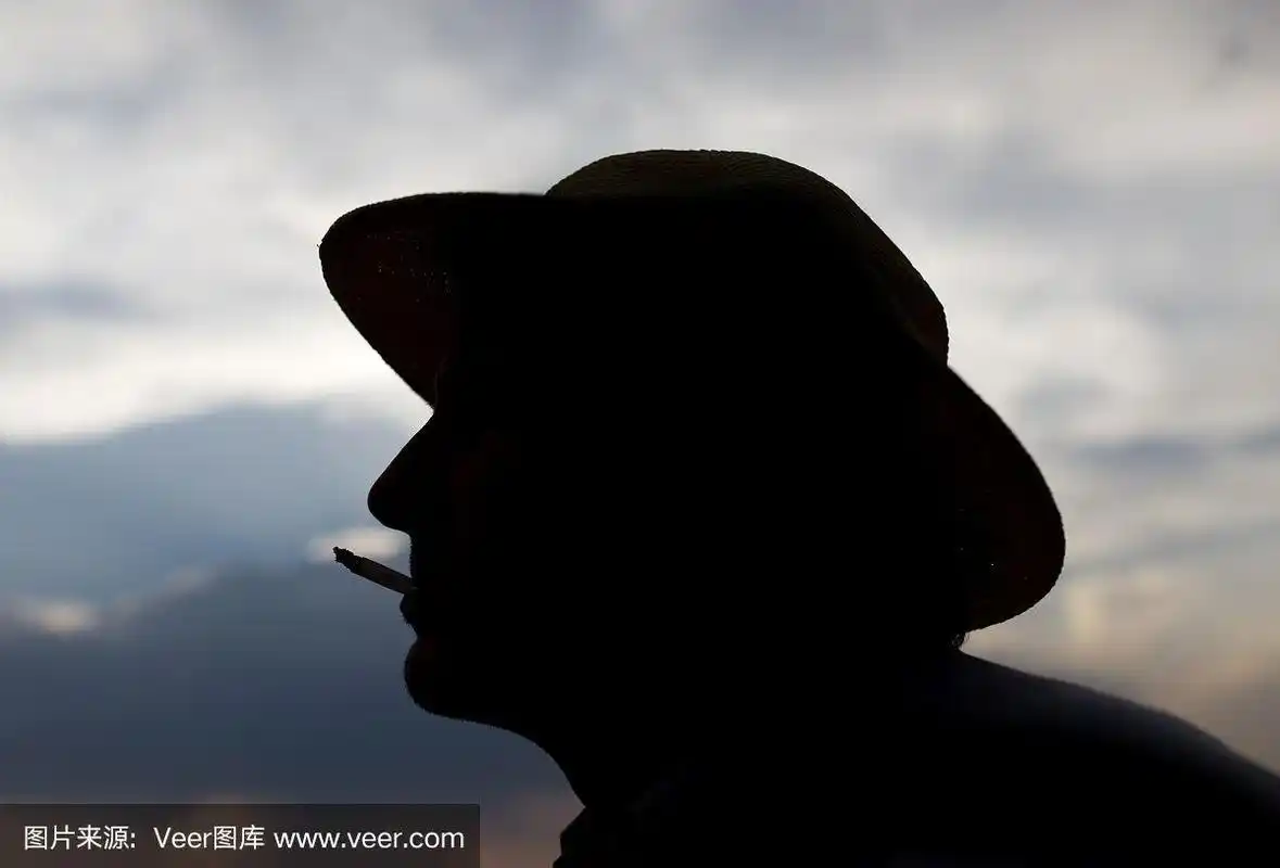 在日落的背景上,一个男人吸烟的剪影