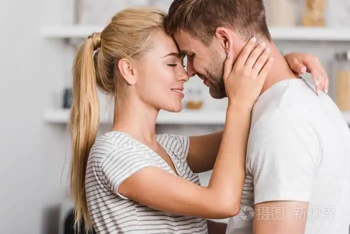 深情情侣拥抱在厨房和额头触摸侧面视图