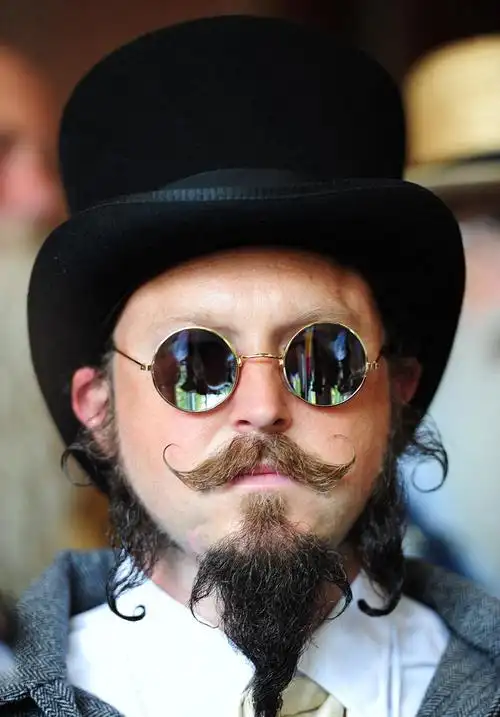 该男子带着黑色礼帽和复古眼镜,独特的胡须造型让他看上去非常的独树