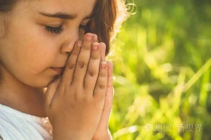 美丽的夕阳下小女孩闭上眼睛在田野里祈祷双手合十祈祷信仰