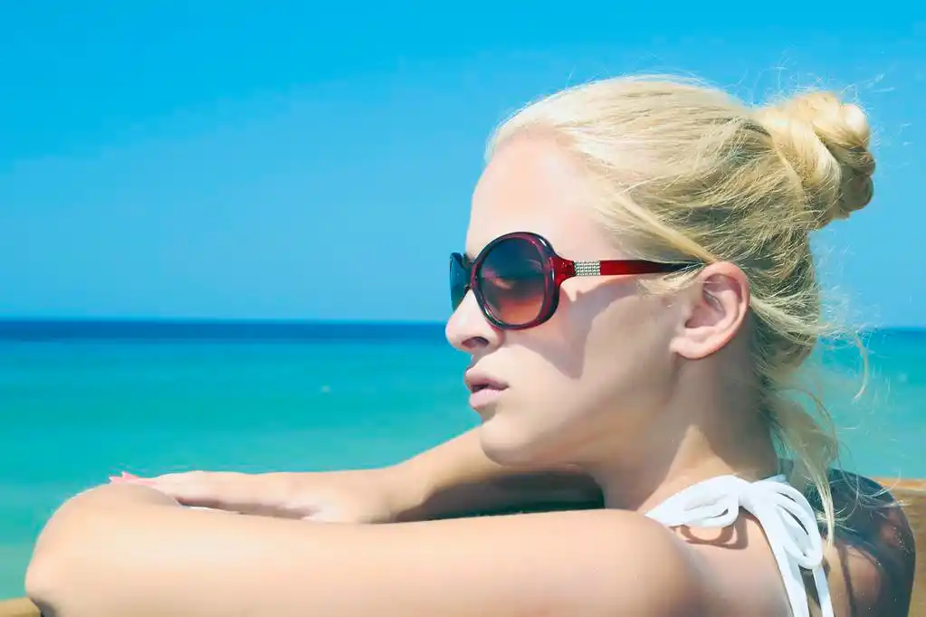 太阳镜在海滩上的金发美女