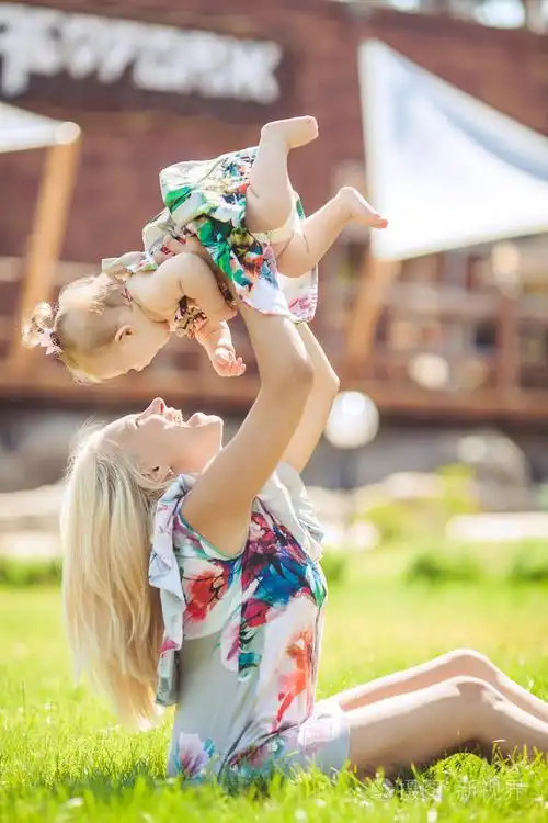 母亲抱着婴儿在夏天绿色公园的画像.户外活动