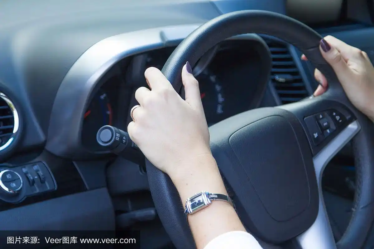 年轻女性的手放在汽车方向盘上
