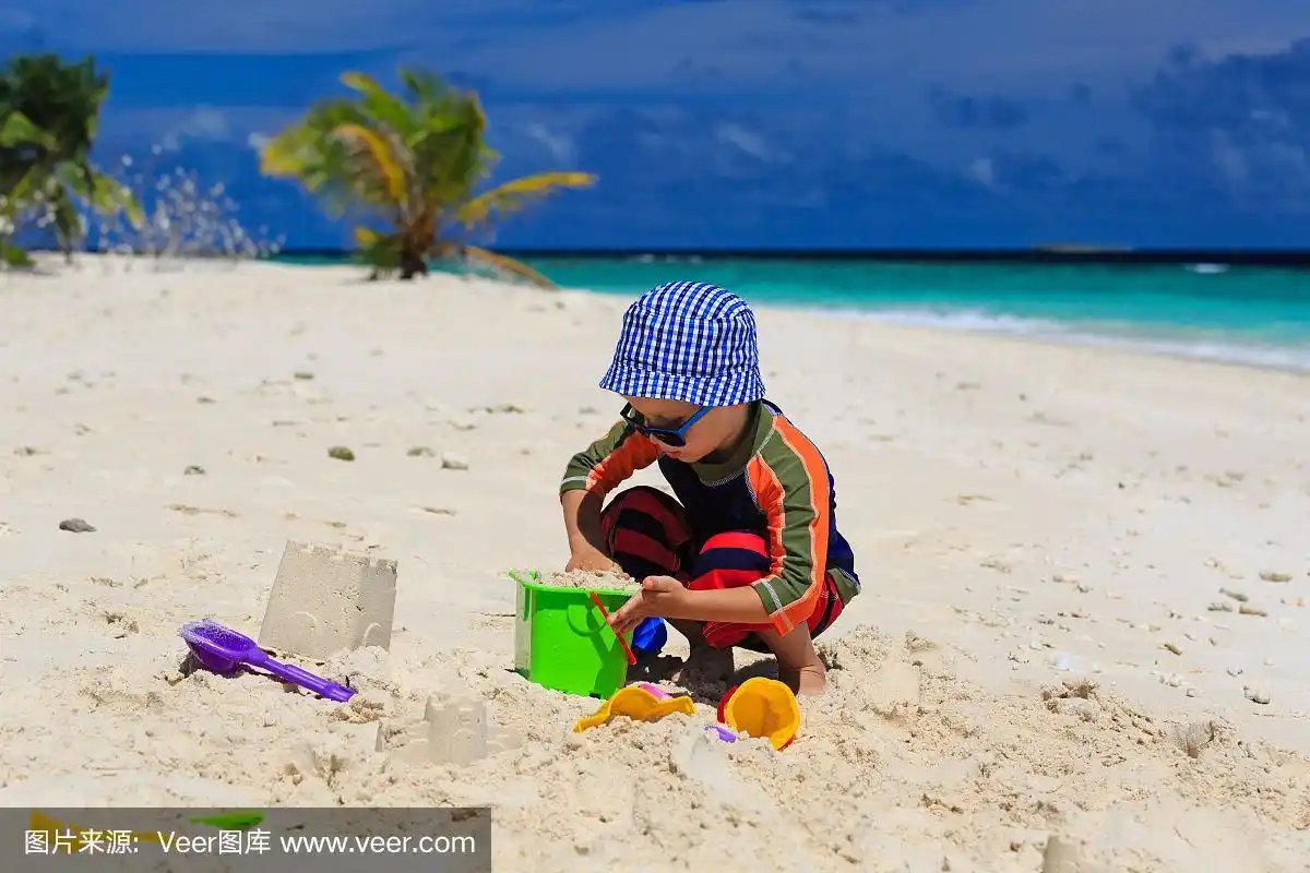 小男孩在热带海滩上玩沙子
