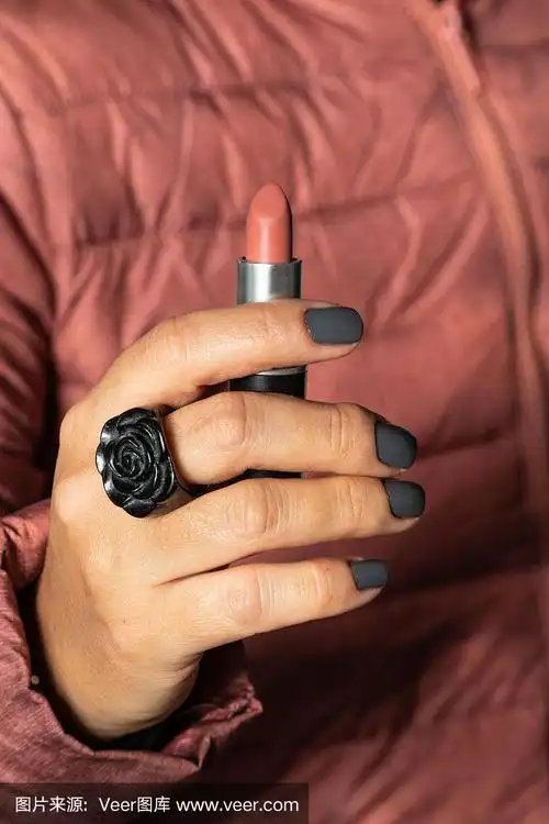 近距离的女人手握红色哑光口红在红色外套的背景.