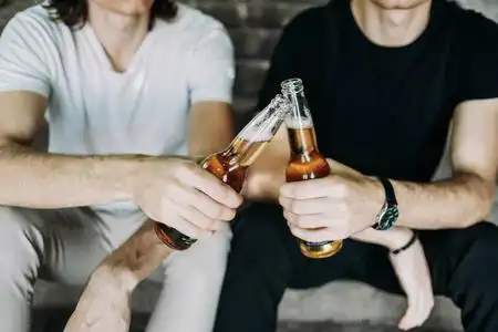 两个时髦的双胞胎兄弟在楼梯上喝啤酒玩得很开心照片