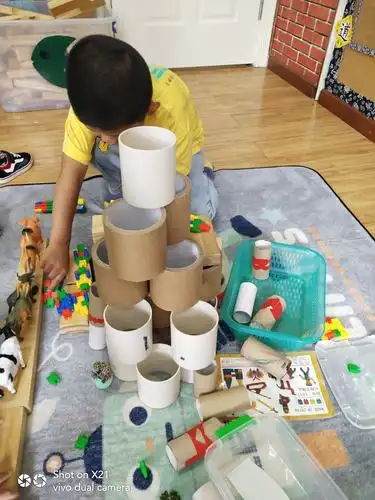 你做完区域计划后,来到建构区,脱掉鞋子,选择了建构区的纸筒和塑料桶