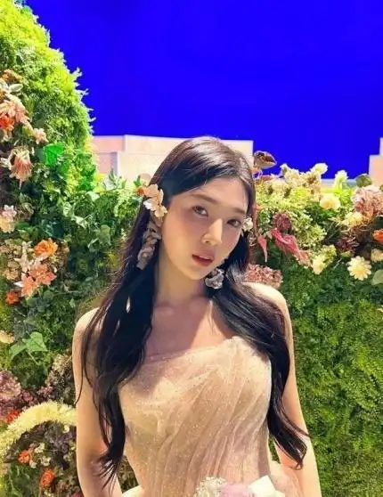 joy身穿华丽的礼服,在背景中摆出各种姿势,摆满了鲜花和草的花园布景.