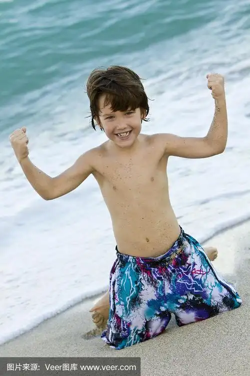 快乐的小男孩在海滩上秀肌肉