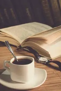 一杯咖啡, 一本打开的书和一张桌子上的钟照片