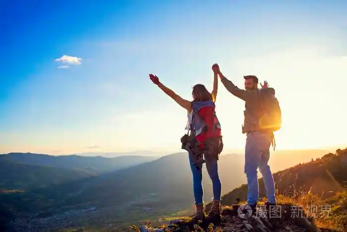 一对快乐的情侣一对男女游客在日落时分在山顶户外徒步旅行