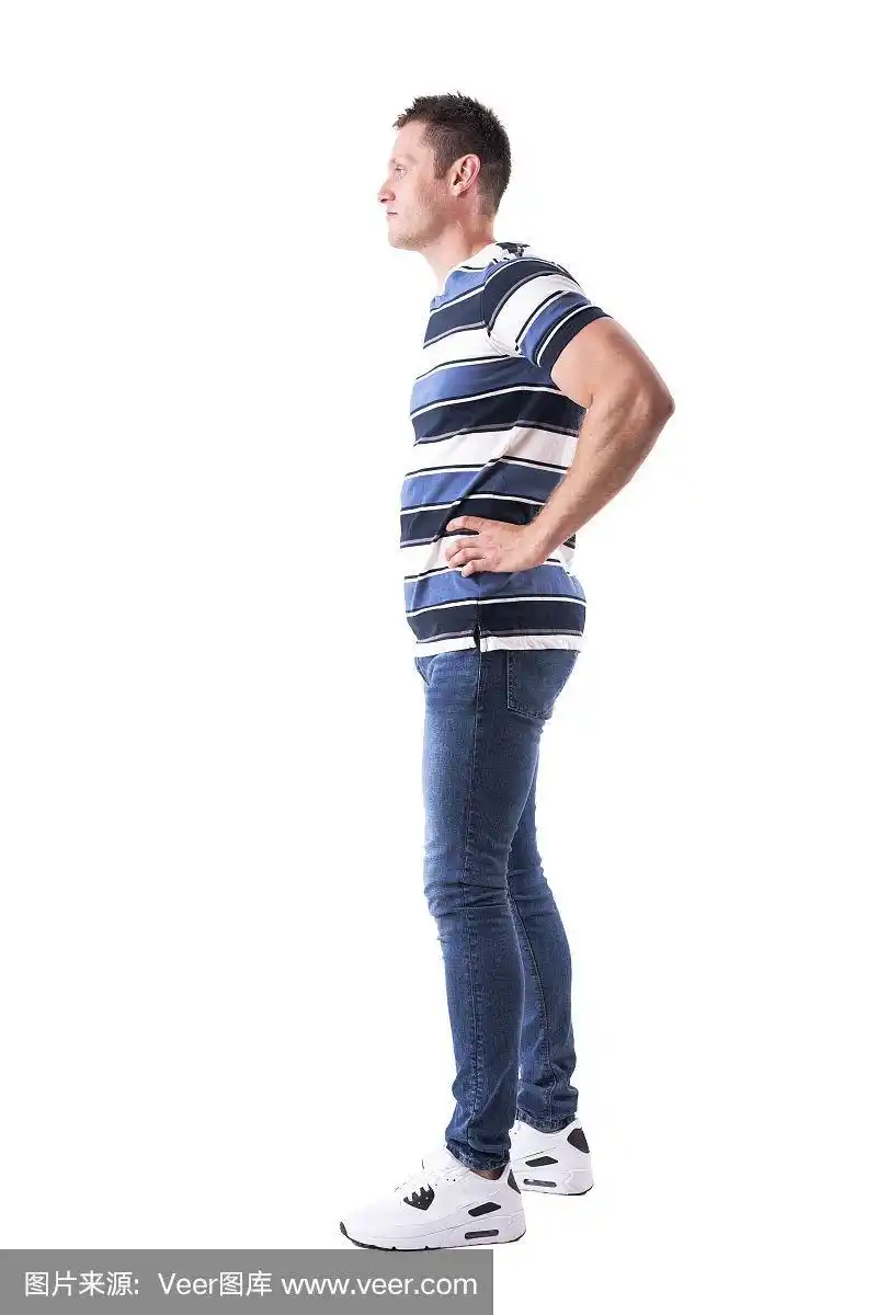 侧面的自信的年轻随意的男人与胳膊在腰部看向别处