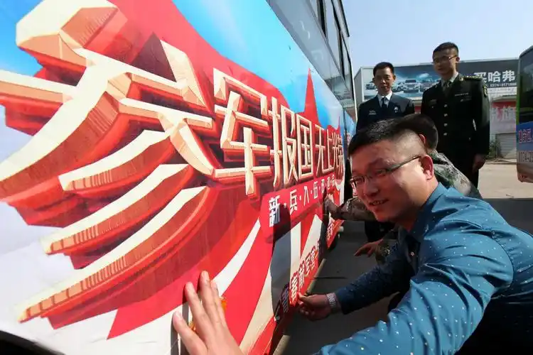 影像 图片新闻   4月29日,工作人员在公交车上张贴征兵宣传招贴画.