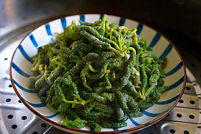 6,蒸到一半的时候,用筷子挑一挑构树花,让构树花无死角全部蒸到,然后