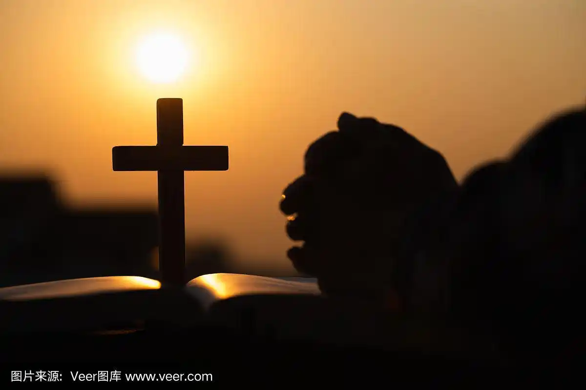 剪影的基督教年轻女子祈祷与十字架和打开圣经在日出