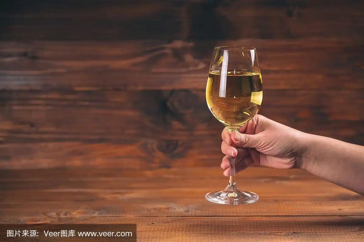 在木制的背景下,女人用白葡萄酒举杯庆祝
