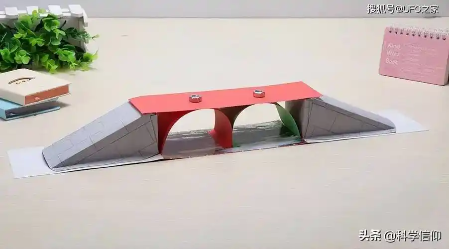 我们用一条硬纸板搭在两张桌子之间做成一个简易的小桥,然后把手机放