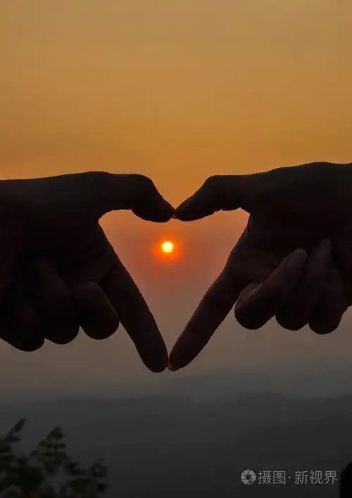 剪影在中间在心形手与日出