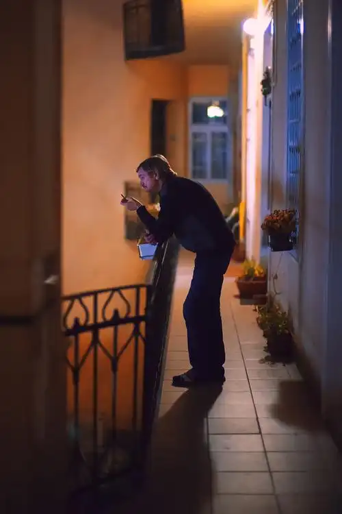 出门看见他在阳台上抽烟. 和楼下人群喧闹的声音格格不入.