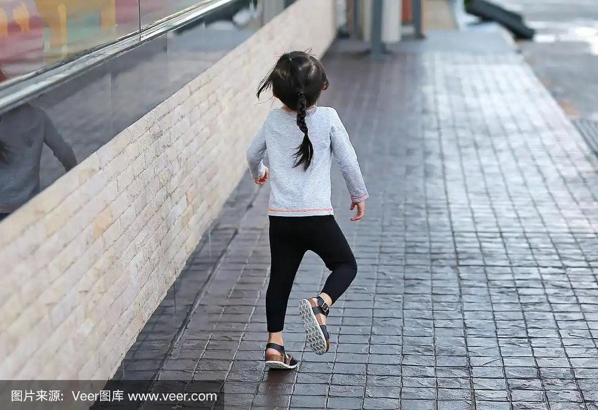 小女孩在人行道上奔跑的背影.