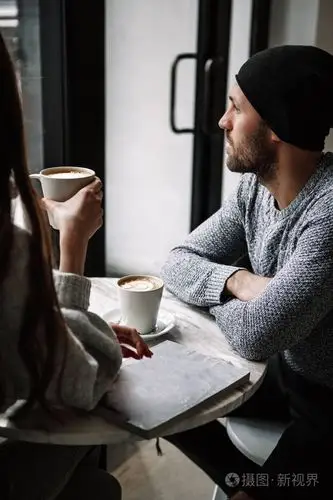 两个快乐的年轻爱喝咖啡的人在咖啡店