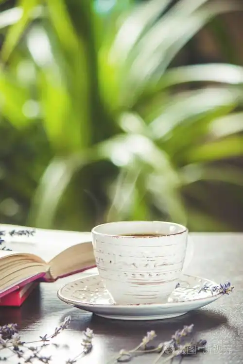 热杯咖啡和在休闲阅读一本书选择性的焦点