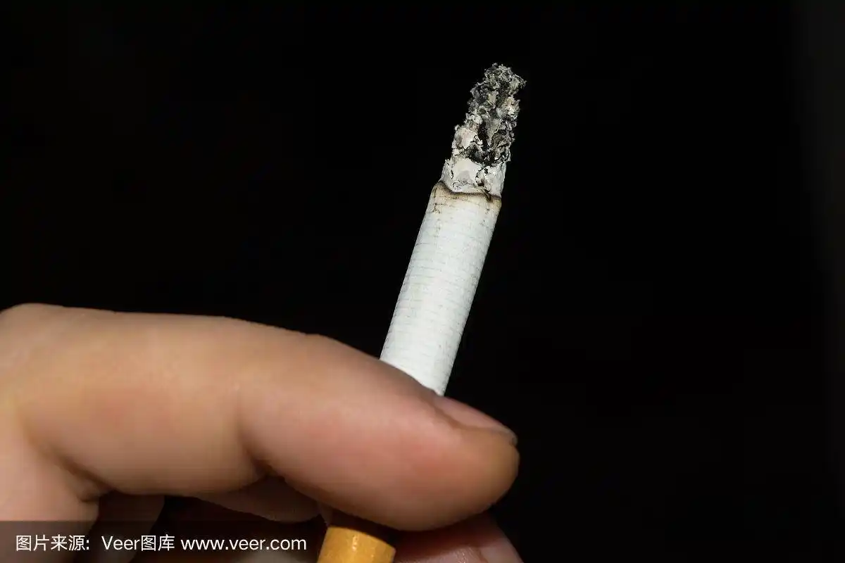 男性手指间夹着冒烟的香烟,黑色背景