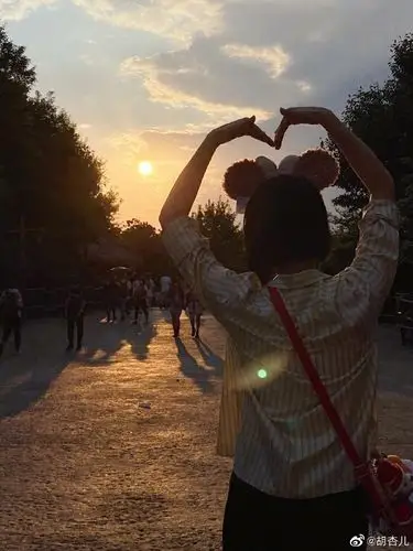 一直玩到傍晚的胡杏儿整个人依旧精力充沛,面对夕阳比心拍下背影中