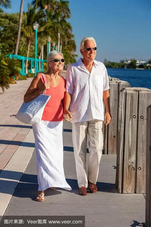 快乐的老年男女浪漫的夫妇携手散步,看着热带海洋或河与明亮的清澈的