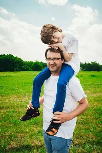 在公园里休息时,微笑着的小男孩和他英俊年轻的爸爸.