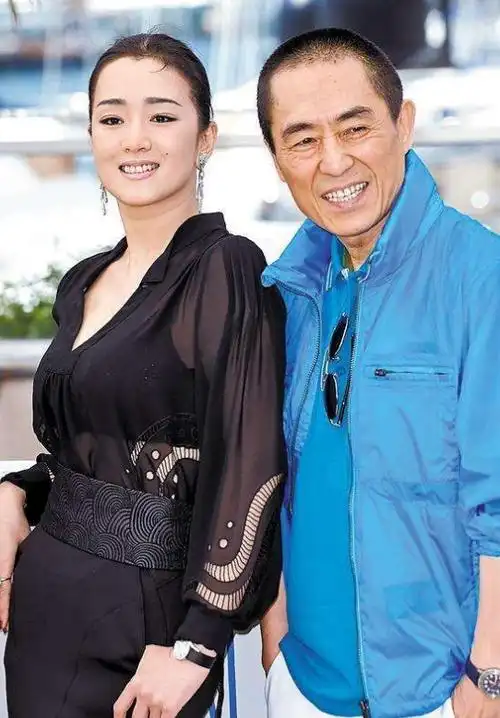 71岁张艺谋走机场,全黑休闲装国旗图案成亮点,小娇妻比巩俐温柔