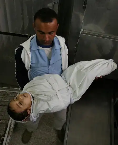 在加沙一所医院的太平间里,一名巴勒斯坦男子抱着被打死男孩的尸体