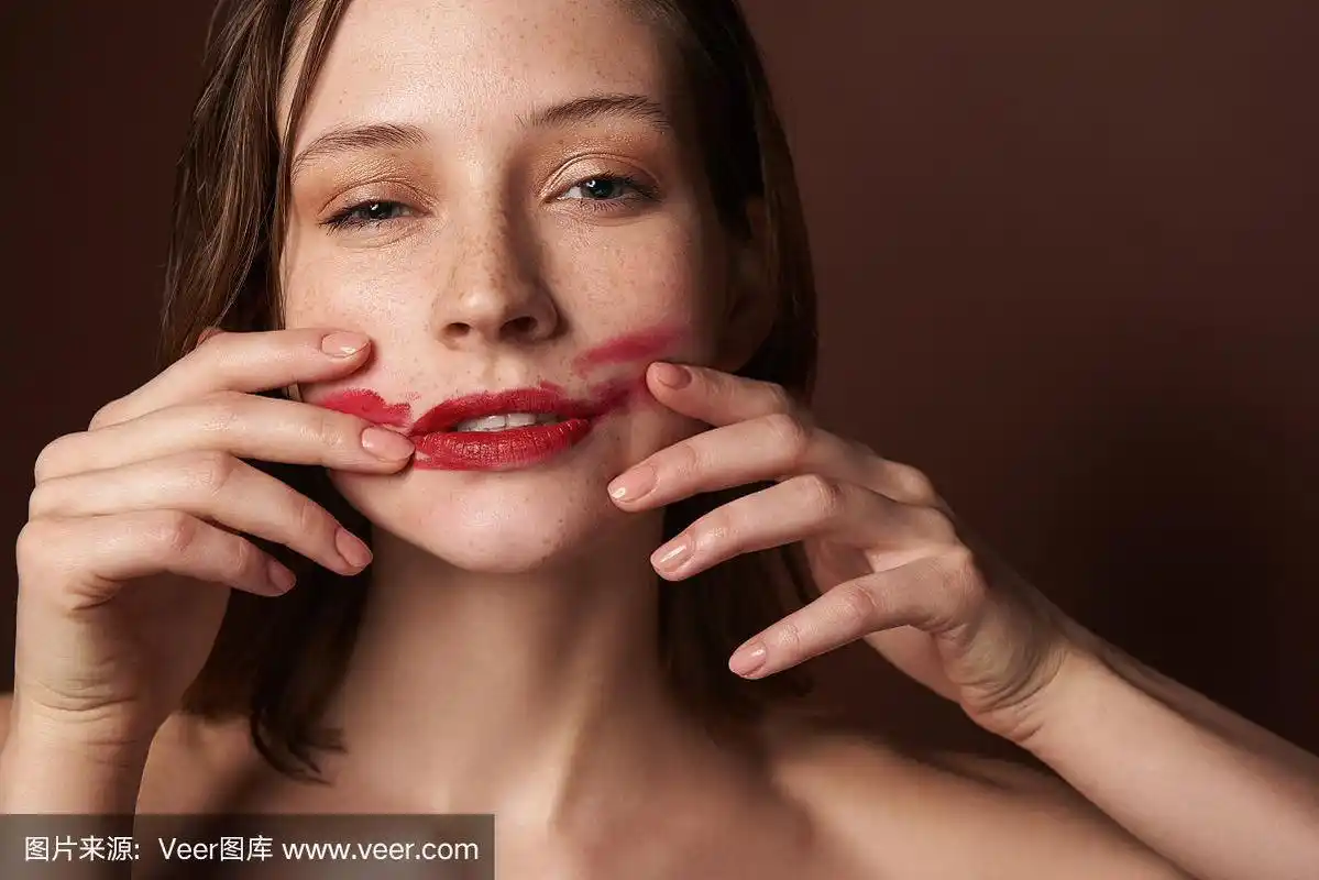 年轻漂亮的女性在脸上涂口红
