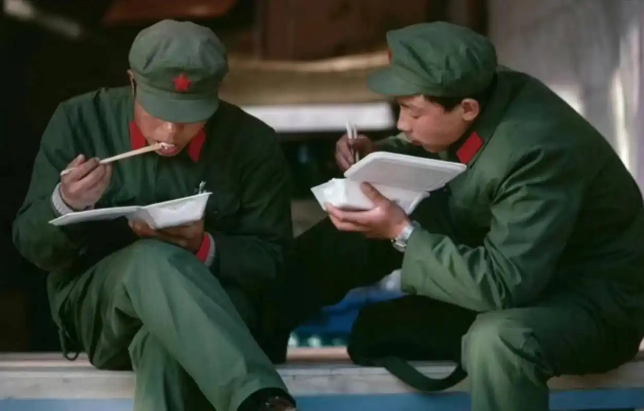 1985年,北京街头,两名身穿六五式军装的解放军战士,正在吃盒饭!