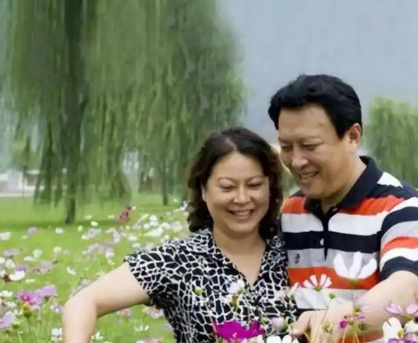 起来皮肤白皙,神采奕奕,身旁的妻子笑容满面,两人亲切和饭店厨师合影