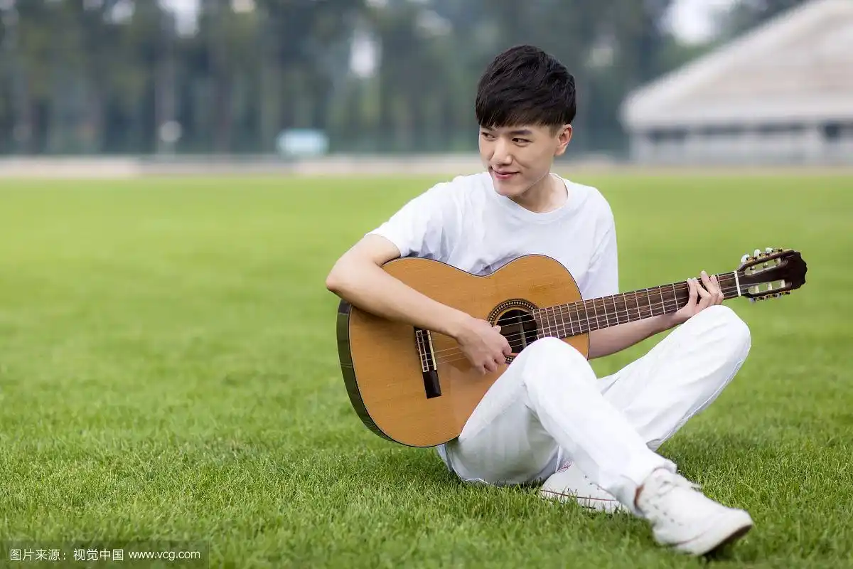 坐着弹吉他的男学生