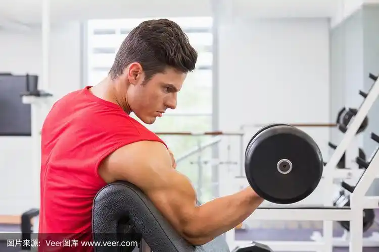 肌肉男在健身房用哑铃锻炼
