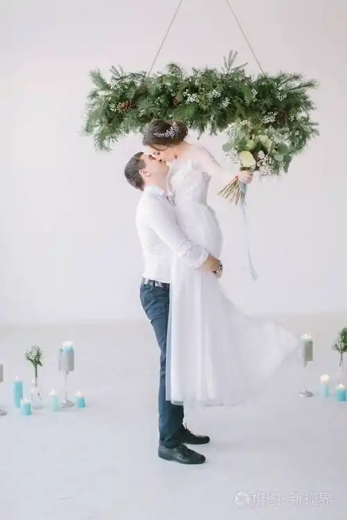 新郎把新娘抱起来.新娘穿着豪华的白色婚纱在新郎怀里笑.